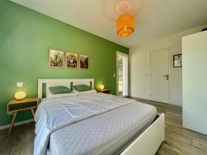 - une chambre avec un grand lit et un mur vert dans l'établissement Havre de paix à 20 min de Nice, à Contes
