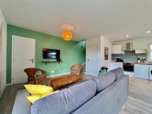 a living room with a blue couch and a kitchen at Évasion Tranquille à 20 min de Nice in Contes