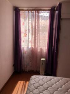 a bedroom with a bed and a window with purple curtains at departamento Iquique in Iquique