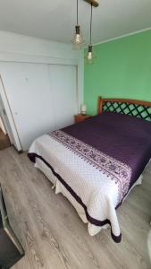 a bedroom with a bed with a purple and white comforter at departamento Iquique in Iquique