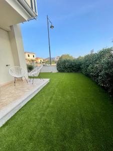 two chairs on a patio with a green lawn at Casa Fralia in Olbia