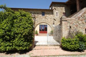 ein Tor zu einem Steinhaus mit einer roten Tür in der Unterkunft Podere Le Muricce in Siena