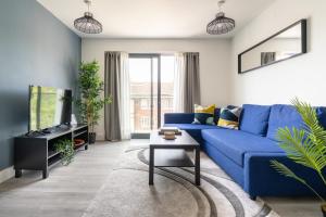 a living room with a blue couch and a tv at Oasis at Hemel Hempstead in Hemel Hempstead