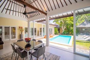 a dining room with a table and chairs and a pool at Sitara Villa in Seminyak