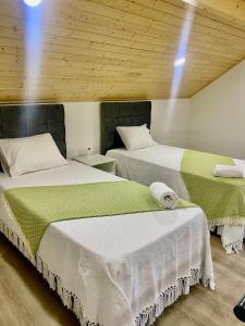 two beds with white and green sheets in a room at Casa das Varzielas in Mondim de Basto