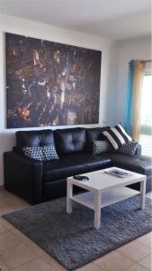 uma sala de estar com um sofá preto e uma mesa de centro em Vilamoura Charming Modern Condominium em Quarteira