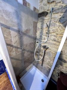 a shower in a bathroom with a stone wall at La Maison De Blanche Neige in Assignan