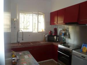eine Küche mit roten Schränken, einem Waschbecken und einem Fenster in der Unterkunft 3 bedrooms house at Alcanar 100 m away from the beach with terrace and wifi in Alcanar