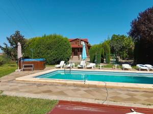 a swimming pool with chairs and a table and an umbrella at 5 bedrooms chalet with shared pool jacuzzi and terrace at Alcaniz in Alcañiz