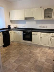 cocina con armarios blancos y lavavajillas negro en The Flat in central Kirkby Stephen en Kirkby Stephen