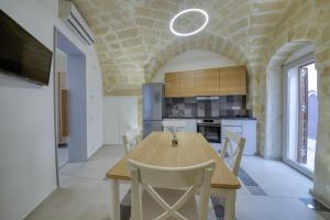 Il comprend une cuisine et une salle à manger avec une table et des chaises en bois. dans l'établissement Palazzo Fondo Vico - Affitti Brevi Italia, à Gravina in Puglia