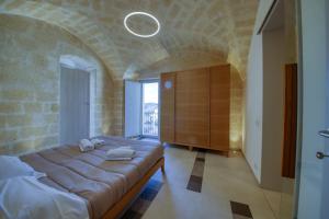 - un grand lit dans une chambre dotée d'un mur en pierre dans l'établissement Palazzo Fondo Vico - Affitti Brevi Italia, à Gravina in Puglia