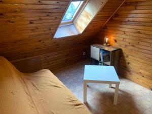 a attic room with a bed and a table at Le Cantou in Castelnau-de-Mandailles