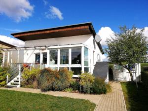 a small white house with a large window at Ferienhaus am See mit Ruderboot in Mustin