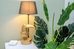 uma lâmpada sentada numa mesa ao lado de uma planta em Le Tropicana - Proche Roissy CDG - Paris - Astérix em Dammartin-en-Goële
