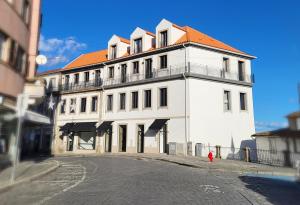 een wit gebouw met een oranje dak op een straat bij Apartamentos do Mercado in Covilhã