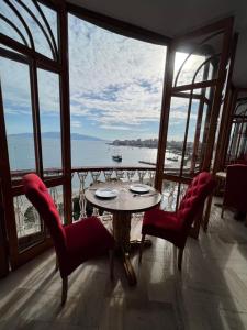 una mesa y sillas en una habitación con vistas al océano en Monte Cristo Hotel with rooftop pool, en Sarandë