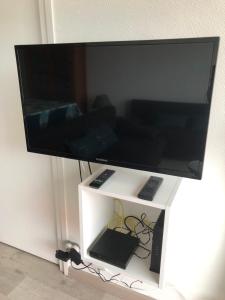 a large flat screen tv on a white stand at LES BALCONS ROUGES - VUE MER in Sainte-Cécile-Plage