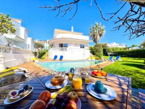 Una mesa con comida y bebidas junto a una piscina. en Vilamoura Brightness Villa With Pool by Homing, en Vilamoura