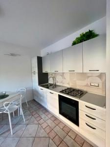 uma cozinha com armários brancos, uma mesa e um fogão em Casa Fralia em Olbia