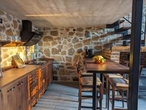 eine Küche mit einem Holztisch und einer Steinmauer in der Unterkunft Kompleks Etno Luks 