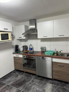 a kitchen with white cabinets and stainless steel appliances at Kuscheliges Einfamilienhaus in Lingenfeld +9 photos
