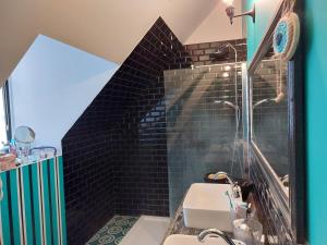 La salle de bains est pourvue d'un lavabo et d'un mur en carrelage noir. dans l'établissement Le Quatorze bis, à Compiègne