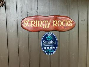 two signs on a fence with a synergy rocks sign at Stringy Rocks in Morenish
