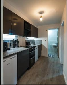Il comprend une cuisine avec des appareils en noir et blanc et du parquet. dans l'établissement Spacious 2 Bedroom Apartment near Seafront, à Penzance