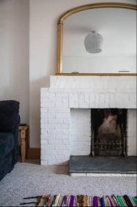 - une cheminée en briques blanches avec un miroir au-dessus dans l'établissement Spacious 2 Bedroom Apartment near Seafront, à Penzance