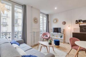 ein Wohnzimmer mit einem Sofa und einem Tisch in der Unterkunft Appartement cosy proche Arc de Triomphe - 4P in Paris