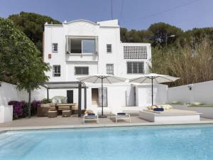a swimming pool with umbrellas and a house at CASA CANYET con piscina a un paso de Barcelona y la playa in Badalona