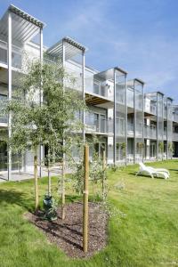 un edificio de apartamentos con un árbol delante de él en Kolgården - Visby Lägenhetshotell en Visby