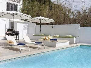 einen Pool mit zwei Stühlen und Sonnenschirmen neben einem Pool in der Unterkunft CASA MODERNISTA CON PISCINA CANYET in Barcelona