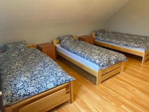 3 łóżka w pokoju z drewnianą podłogą w obiekcie Domek pod lasem w mieście Kańczuga