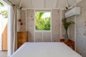 1 dormitorio con cama blanca y ventana en One bedroom bungalow with shared pool terrace and wifi at Saint Barthelemy, en Saint Barthelemy