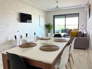 ein Esszimmer und ein Wohnzimmer mit einem Tisch und Stühlen in der Unterkunft luxe appartement met zeezicht en zwembad Mohammedia Parc in Mohammedia