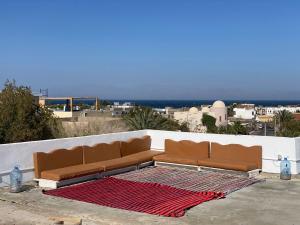 un canapé brun assis sur un mur avec un tapis rouge dans l'établissement Shabana House, à Dahab
