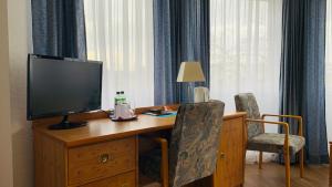 Zimmer mit einem Schreibtisch, einem TV und 2 Stühlen in der Unterkunft Hotel Garni in Rosbach vor der Höhe
