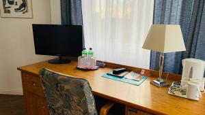 a desk with a computer monitor and a lamp on it at Hotel Garni in Rosbach vor der Höhe