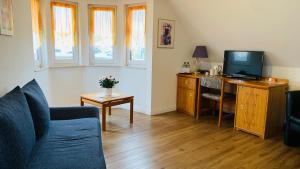 ein Wohnzimmer mit einem Sofa und einem TV in der Unterkunft Hotel Garni in Rosbach vor der Höhe