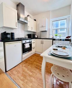 a kitchen with white cabinets and a table with wine glasses on it at Gorgeous Studio 15 Minutes from Central London in London