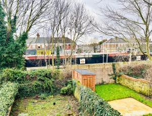 a garden with a fence and a train in the background at Gorgeous Studio 15 Minutes from Central London in London