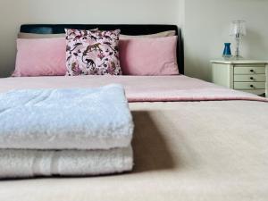 a bed with pink and white sheets and pillows at Gorgeous Studio 15 Minutes from Central London in London