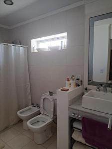 a white bathroom with a toilet and a sink at Cómodo departamento en el bajo neuquino in Neuquén