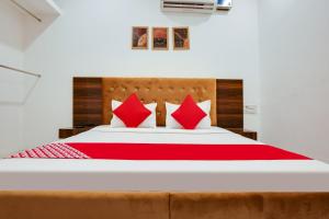 um quarto com uma cama grande e almofadas vermelhas em Flagship Hotel Cozy Comfort em Ludhiana