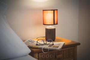 eine Lampe auf dem Tisch mit einer Zeitung und einem Buch in der Unterkunft Oasi Marina Apartment Sea View by Diddoi in Torre Suda