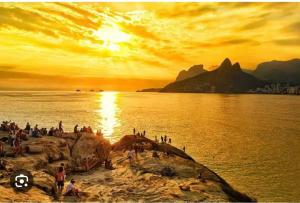 un grupo de personas de pie sobre una roca en el agua en Venha se hospedar no bairro que tem a 2ª melhor praia do mundo e o pôr do sol mais lindo do planeta!, en Río de Janeiro