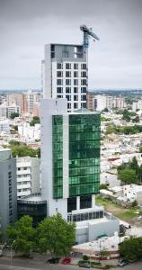 a tall white building with green windows in a city at Amerian Rio Cuarto Apart & Suites in Río Cuarto