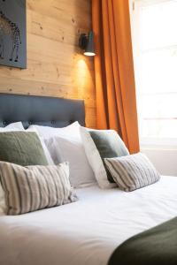a bed with white pillows and an orange curtain at OURAL Annecy Rent Lodge in Annecy